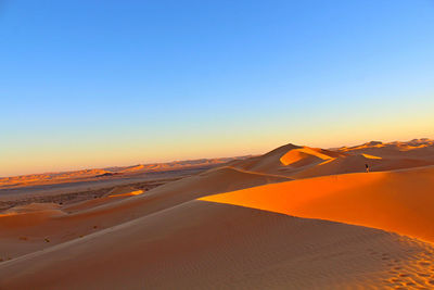 Scenic view of desert against clear sky at sunset