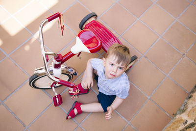 High angle view of boy crying while sitting on tiled floor