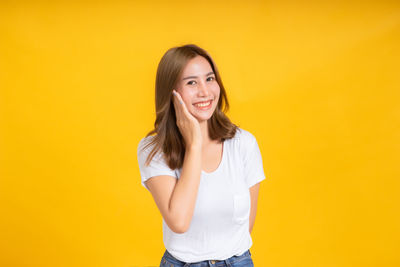 Portrait of a smiling young woman against yellow background