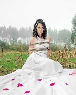 Portrait of young woman with arms raised on field