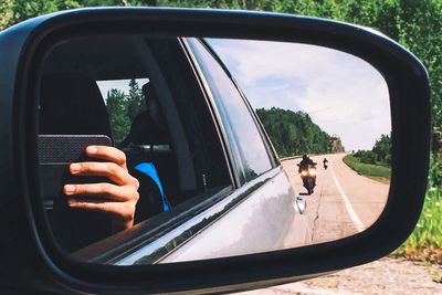 Reflection of people on side-view mirror of car