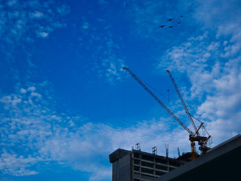 Low angle view of crane against blue sky