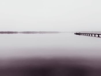 Scenic view of river against clear sky during foggy weather