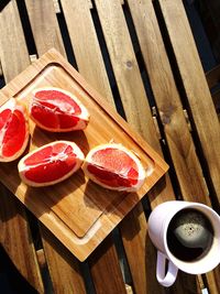 High angle view of sliced grapefruits on wooden tray with black coffee