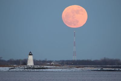 View of tower at waterfront against moon clear sky