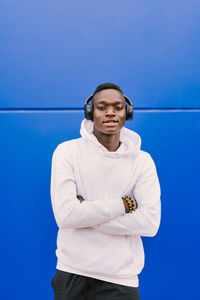 Portrait of young man standing against blue wall