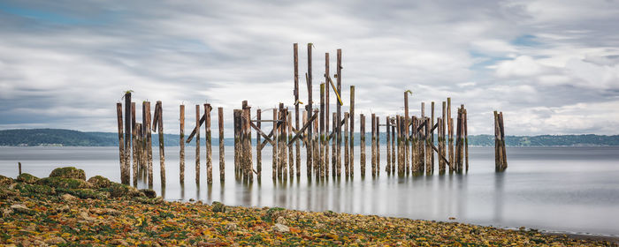 Wooden posts on beach against sky