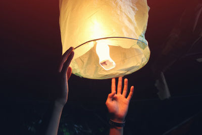 Close-up of hand holding paper lantern at night