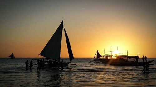 Sailboat in sea at sunset