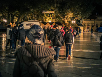 People walking on wet street in city at night