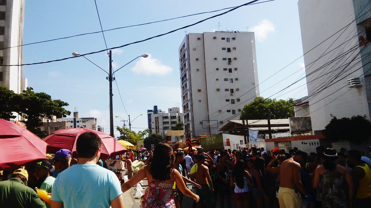 large group of people, building exterior, architecture, men, built structure, person, lifestyles, crowd, city, street, city life, leisure activity, sky, mixed age range, walking, building, tree, city street, crowded