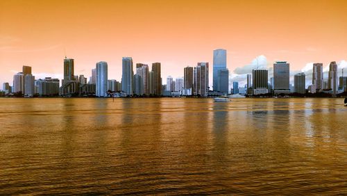 Modern buildings in city against sky during sunset