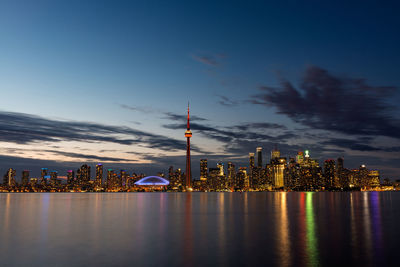 Lake ontario in front of illuminated city against sky