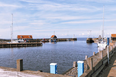 Sailboats moored at harbor against sky