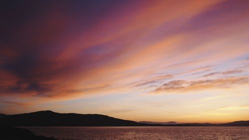 Scenic view of sea against dramatic sky during sunset