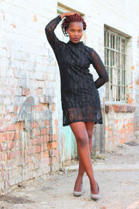 Portrait of smiling young woman against brick wall