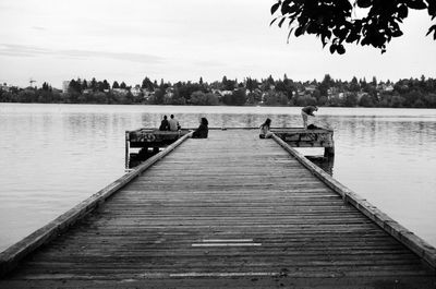Pier sitting on jetty by lake against sky