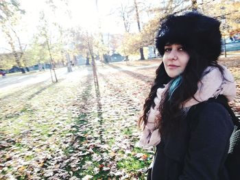 Portrait of young woman standing on tree trunk