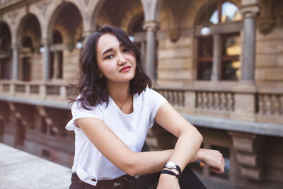 Young asian woman, smiling, architecture in the background. street portrait, lifestyle concept
