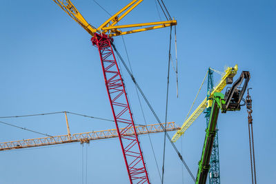 Low angle view of crane against clear blue sky