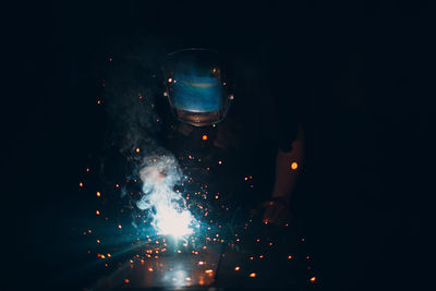 Blurred motion of man holding illuminated fire in dark room