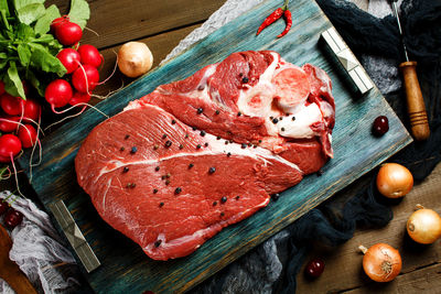 Fresh beef veal meat on rustic wooden table with fresh vegetables, top view