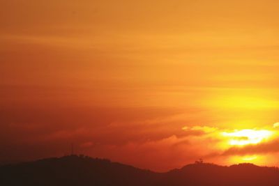 Scenic view of silhouette mountains against orange sky