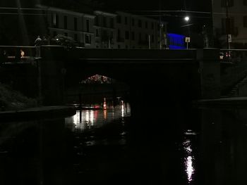 Illuminated bridge over river in city at night