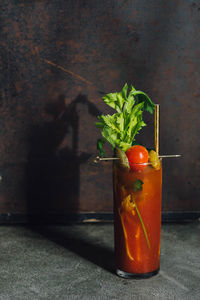 Bloody mary tomato brunch cocktail drink with celery, lemon, rosemary, pickles, olives, gold straw
