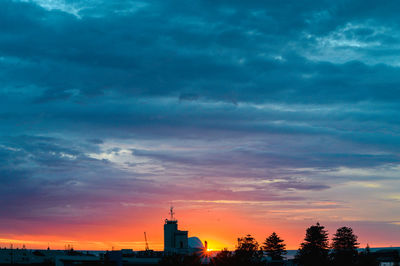 Silhouette of buildings against cloudy sky