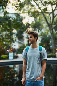 Young man standing by pond in city