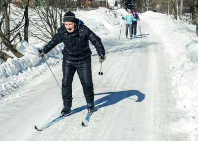 Family skiing on snow covered road