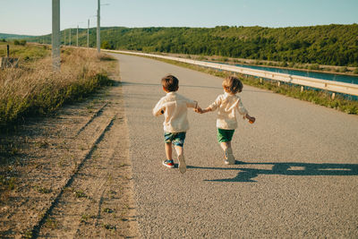 Rear view of boy running on road