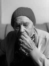 Close-up of senior woman with eyes closed sitting on sofa at home