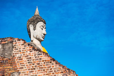 Low angle view of statue of building against blue sky