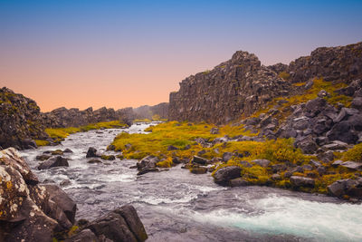 Scenic view of rocks in sea against clear sky