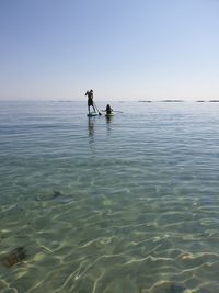 People on sea against clear sky
