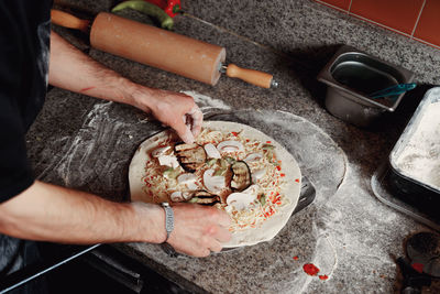 Cropped hand of person preparing pizza