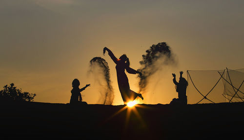 Silhouette people standing against sky during sunset