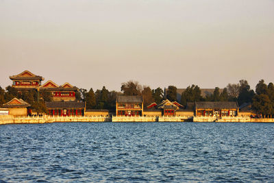 Houses by lake and buildings against clear sky