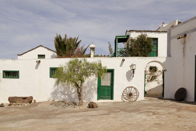 Old house by street against sky on sunny day