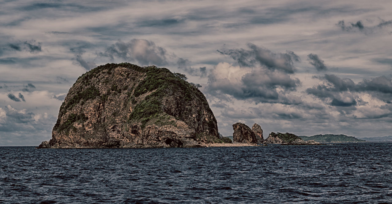 ROCK FORMATION ON SEA AGAINST SKY