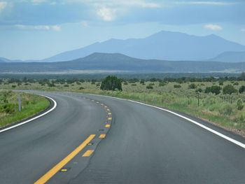 Empty road by mountains against sky