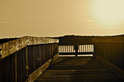 Footbridge against sky during sunset