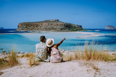 Rear view of woman on beach against sky