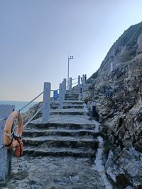 Man on staircase by mountain against clear sky