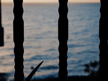 Low section of silhouette bare tree against sea