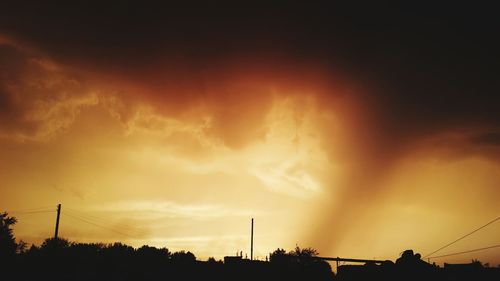 Low angle view of power lines against cloudy sky