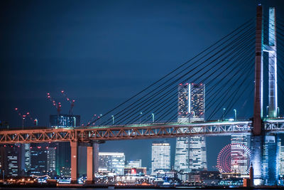 Illuminated bridge over river at night