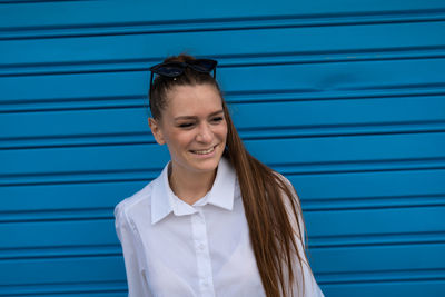 Portrait of smiling young woman standing against blue wall